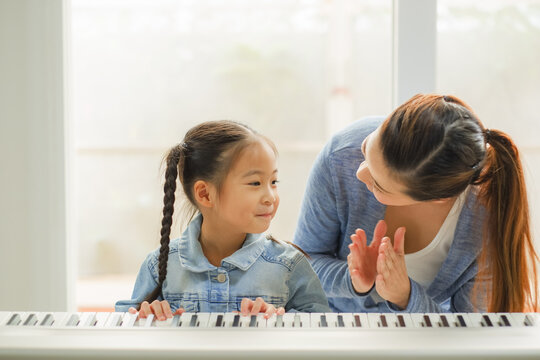 Single mom and daughter playing music with electric piano