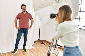 Handsome model posing for professional photographer woman at photography studio.