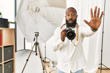 African american photographer man working at photography studio doing stop gesture with hands...