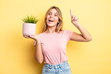 pretty blonde girl feeling like a happy and excited genius after realizing an idea. houseplant...