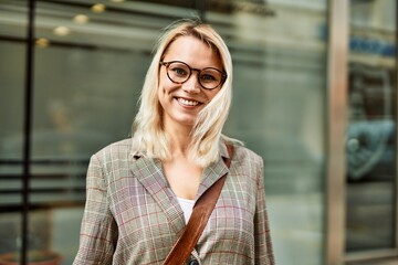 Young blonde businesswoman smiling happy standing at the city.