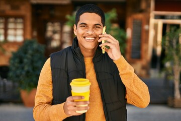 Young latin man talking on the smartphone and drinking coffee at the city