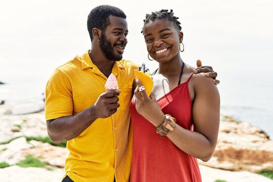 Young African American Couple Smiling Happy Eating Ice Cream At The Beach.