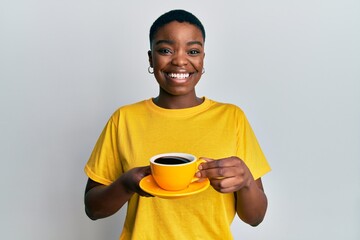 Young african american woman holding coffee winking looking at the camera with sexy expression,...