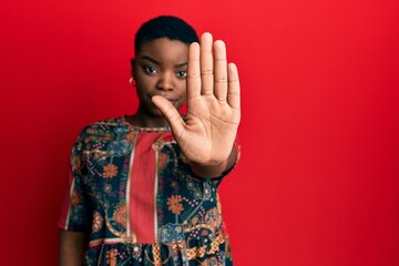 Young african american woman wearing african style doing stop sing with palm of the hand. warning expression with negative and serious gesture on the face.