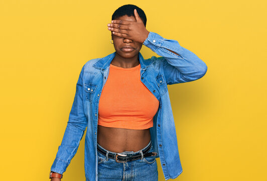 Young african american woman wearing casual clothes covering eyes with hand, looking serious and sad. sightless, hiding and rejection concept