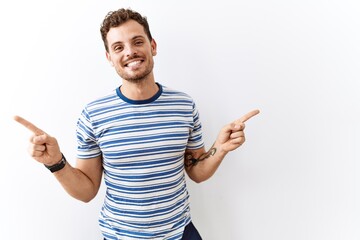 Handsome young man standing over isolated background smiling confident pointing with fingers to different directions. copy space for advertisement