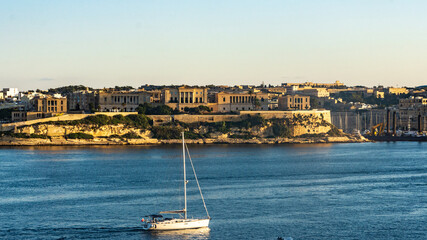 A yacht in the Grand Harbour sailing pass the former Royal Naval Hospital Bighi, in Kalkara, Malta.