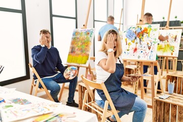 Group of middle age artist at art studio yawning tired covering half face, eye and mouth with hand....
