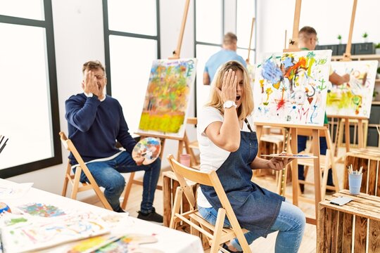 Group of middle age artist at art studio yawning tired covering half face, eye and mouth with hand. face hurts in pain.