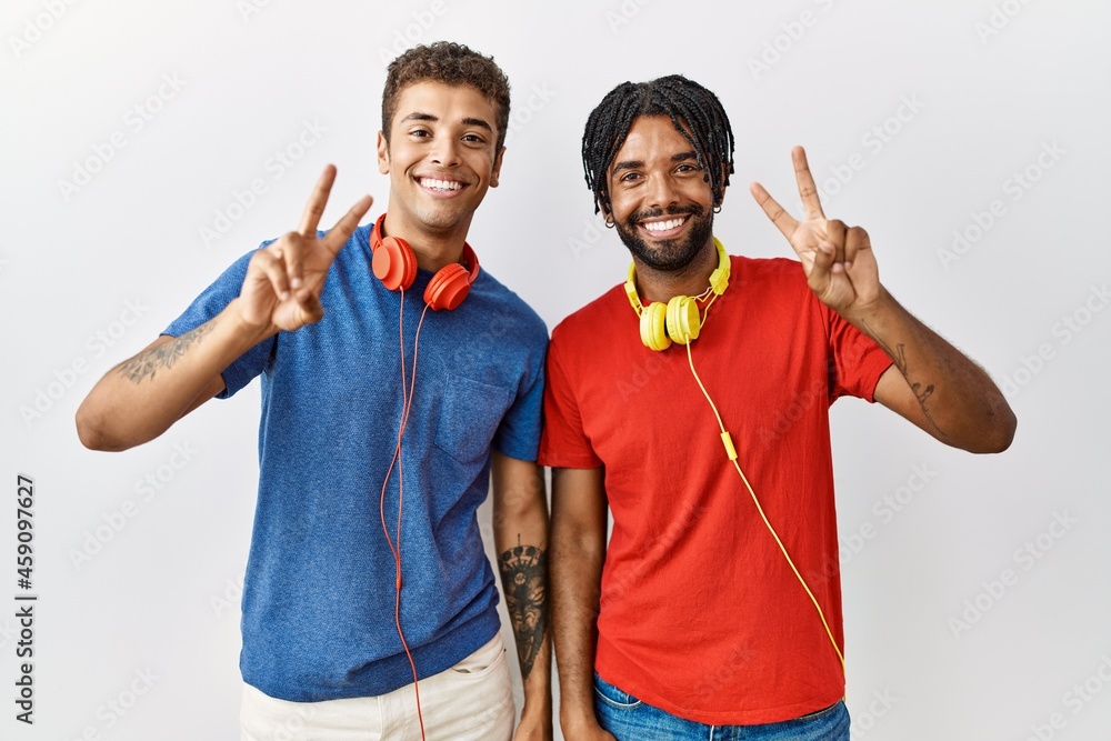 Sticker young hispanic brothers standing over isolated background wearing headphones smiling looking to the 