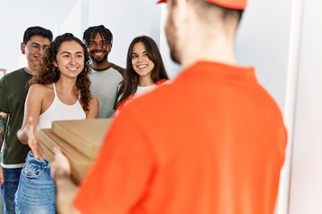 Group of people holding take away pizzas from deliveryman at home.