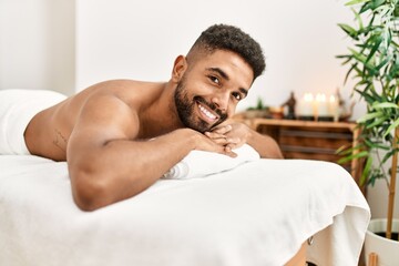 Young african american smiling happy relaxed lying on massage table at beauty center.