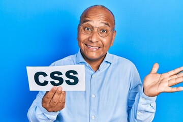 Middle age latin man holding css message paper celebrating achievement with happy smile and winner expression with raised hand