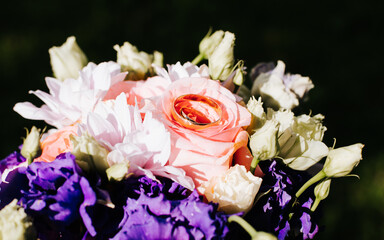 Wedding day, proposal of marriage concept. Close-up of two gold wedding rings lie on rose inside bouquet of flowers outdoors, top view