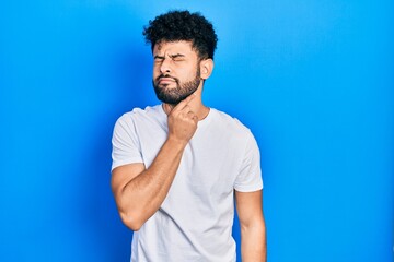 Young arab man with beard wearing casual white t shirt touching painful neck, sore throat for flu, clod and infection