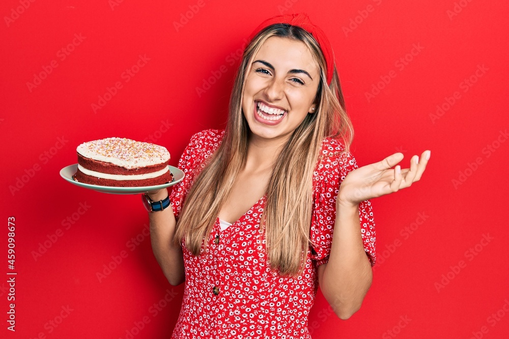 Poster Beautiful hispanic woman holding strawberry cake celebrating achievement with happy smile and winner expression with raised hand