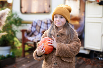 Happy Halloween. Smiling girl standing on the porch with a pumpkin in her hands. Trick-or-treat....