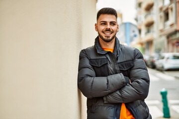 Handsome hispanic man with beard smiling happy and confident at the city wearing winter coat