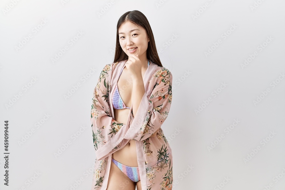 Poster young asian woman wearing bikini an floral kimono looking confident at the camera smiling with cross