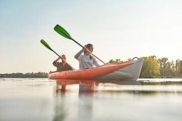 Young woman kayaking together with her boyfriend in a river on a summer day