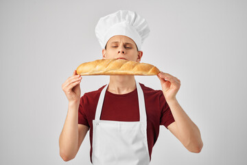 Baker in a white apron loaf in the hands of cooking