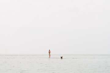 Fototapeta premium woman playing with her dog in the sea water, border terrier, cute little dog 