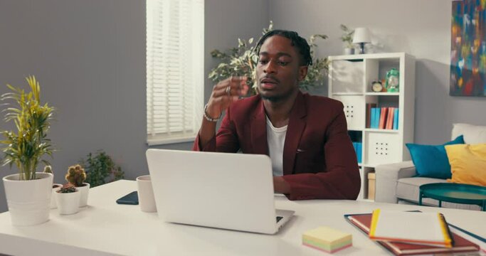 Heartbroken, sad boy sits at company desk in front of laptop, looks up in despair, grabs head, no money, poor paycheck, financial problems, company expenses, horror, headache, stress