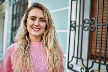 Young blonde woman smiling at the city