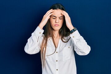 Young brunette teenager wearing casual white shirt suffering from headache desperate and stressed because pain and migraine. hands on head.