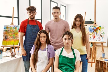 Group of five hispanic artists at art studio skeptic and nervous, frowning upset because of problem. negative person.