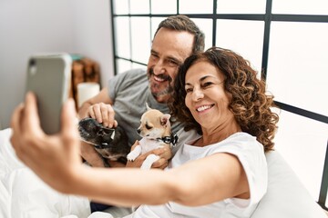 Middle age hispanic couple smiling happy making selfie by the smartphone. Lying on the bed with...