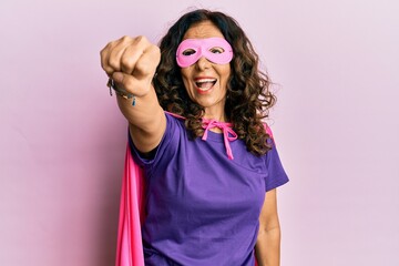 Middle age hispanic woman dressing as superhero wearing pink and purple feminist colors, smiling...