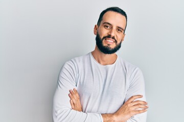 Young man with beard wearing casual white shirt happy face smiling with crossed arms looking at the camera. positive person.