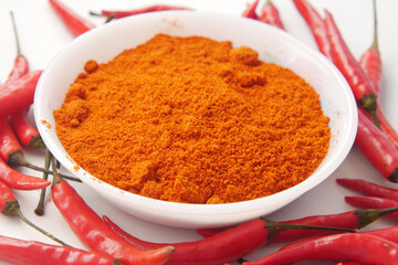 Chili powder and red peppers on table background.