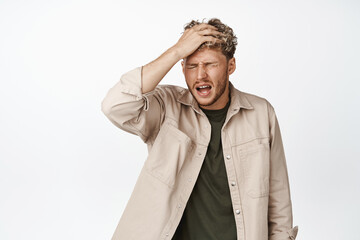 Upset young man slap his forehead forgetful gesture, forgot something, remember, standing over...