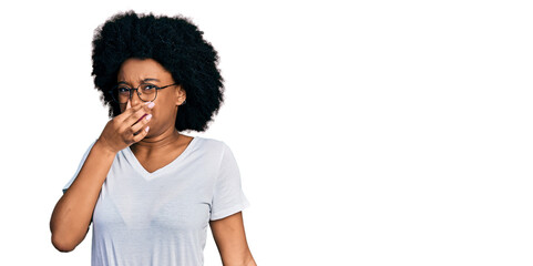 Fototapeta na wymiar Young african american woman wearing casual white t shirt smelling something stinky and disgusting, intolerable smell, holding breath with fingers on nose. bad smell