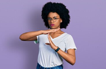 Young african american woman wearing casual white t shirt doing time out gesture with hands,...