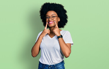 Fototapeta na wymiar Young african american woman wearing casual white t shirt smiling with open mouth, fingers pointing and forcing cheerful smile