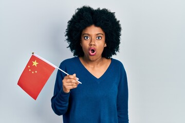 Young african american woman holding china flag scared and amazed with open mouth for surprise, disbelief face