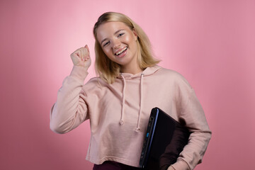 student with glasses and a laptop in her hands, a young cute blonde in a pink sweatshirt