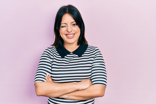 Young hispanic woman with arms crossed gesture winking looking at the camera with sexy expression, cheerful and happy face.