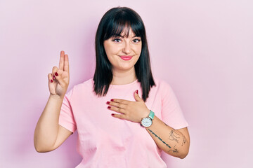 Young hispanic woman wearing casual clothes smiling swearing with hand on chest and fingers up,...
