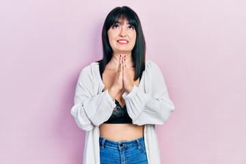 Young hispanic woman wearing lingerie begging and praying with hands together with hope expression on face very emotional and worried. begging.