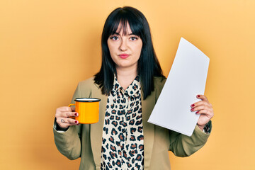 Young hispanic woman wearing business style drinking cup of coffee relaxed with serious expression...