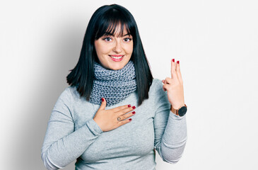 Young hispanic plus size woman wearing winter scarf smiling swearing with hand on chest and fingers...