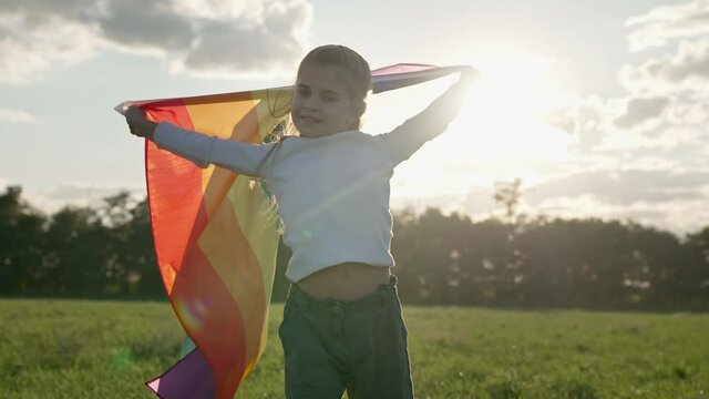 Symbol of love, freedom or LGBT pride concept. Girl holding the rainbow flag against the blue sky background, outdoors in the summer. Liberty right, proud to be equal and legal marriage.