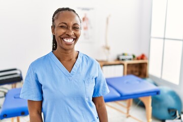 Black woman with braids working at pain recovery clinic winking looking at the camera with sexy...
