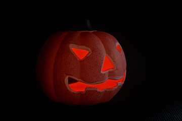 A glowing carved pumpkin in a black background - halloween concept