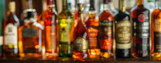 Fototapeten Beautiful bokeh from a row of alcoholic bottles in backlight. © volff